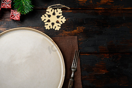 圣诞质朴的家庭餐桌设置，配有空盘子、顶视图平躺、带有文字或食物的复制空间，位于旧的深色木桌背景上
