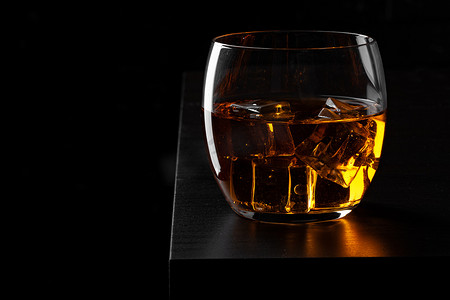 白兰地饮料摄影照片_威士忌玻璃对深黑色垃圾墙