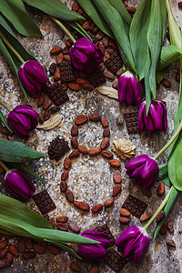 庆典月摄影照片_3 月 8 日，国际妇女节，八颗可可豆，周围有紫色郁金香和手工巧克力