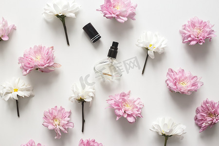 平铺构图，白色背景上有春天的花朵和香水罐。