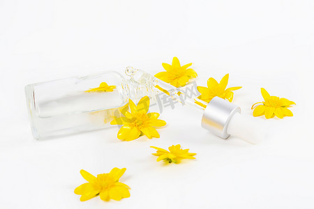 化妆品滴管瓶子摄影照片_黄色春花中白色背景上装有吸管血清的瓶子
