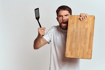 有厨房木板、浅色背景上有铲子的男人情绪白色T恤模型