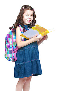 幼儿园故事摄影照片_快乐的小女学生背着背包读书。