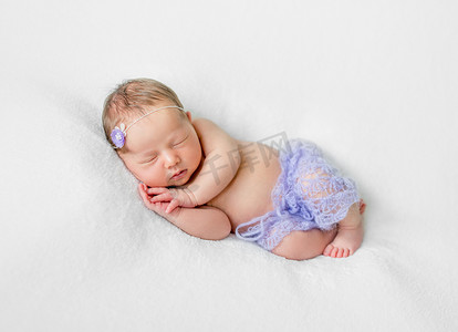 可爱的熟睡新生儿，手放在头下，穿着紫罗兰色内裤
