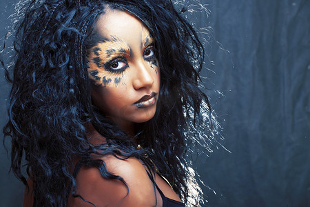 美丽的非洲女孩与猫化妆，创意豹纹脸部特写万圣节女人