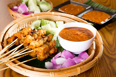 洋葱根尖纵切图摄影照片_鸡肉沙爹配美味的花生酱、ketupat、洋葱和 cuc