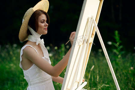 穿白裙子的女人在自然画架上画了一幅画