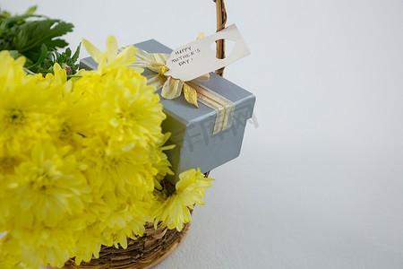柳条篮中的礼盒和一束黄花，上面贴着母亲节快乐的标签