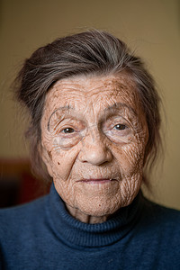 九十岁的白种人老奶奶专注地看着，微笑着，感觉很高兴，大肖像，脸上有深深的皱纹，灰白的头发。
