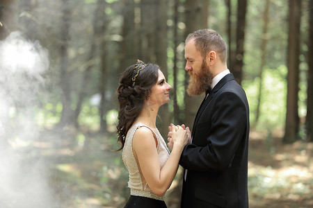 新娘和新郎站在树林里。带有云效果的照片