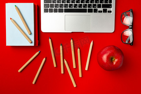 带开放式笔记本电脑和红苹果的学生工作空间的顶视图