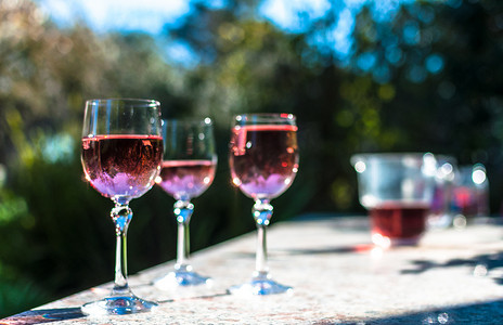 花园桌子上的高脚杯中的桃红葡萄酒