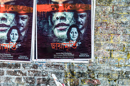 孟加拉语 Tollywood 印度电影海报在城市街道的旧砖墙上。 