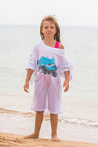 女孩穿着我父亲的衬衫站在海滩上摆出滑稽的表情