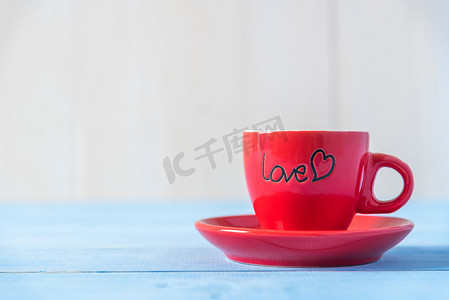 浅蓝色木桌上的红色爱心咖啡杯