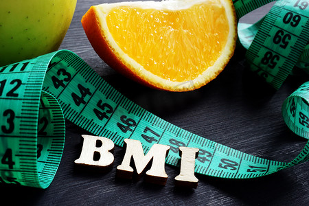 英文字母线稿摄影照片_字母 BMI 体重指数与卷尺和橙色。