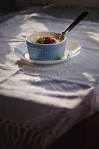 质朴的亚麻桌布上的白色和蓝色盘子里放着薄荷烤燕麦蓝莓碎屑。