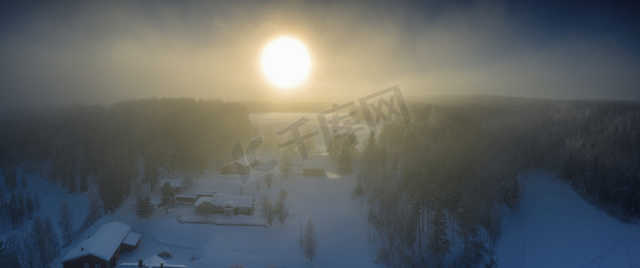 短暂的摄影照片_冬季日落的壮丽景色与非常大的太阳斑在冰冻的雾气中，冬季松树林，空中，格拉诺村，瑞典北部于默奥市周围，短暂的冬日，亚北极景观。