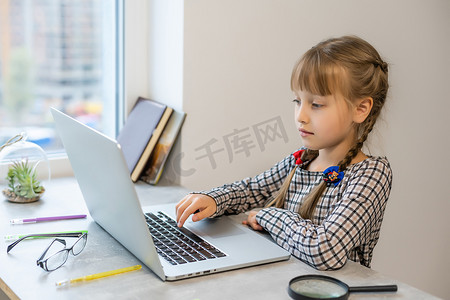 金发小女孩在家里的桌子上做作业。