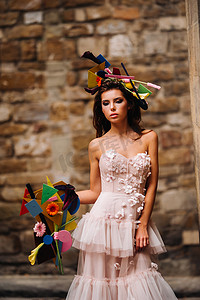 穿着粉红色婚纱的漂亮时尚女孩模特在佛罗伦萨拍摄，手里拿着一束不寻常的花束，新娘模特手里拿着花束，佛罗伦萨新娘的合影。