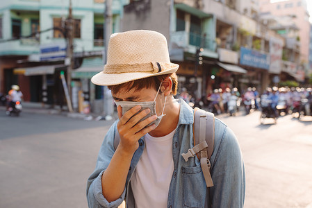 戴着防护面具的年轻人在空气污染的城市街道上感觉很糟糕