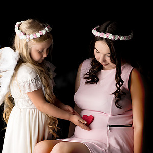 天使形象中的女孩拥抱着她大女儿的肚子