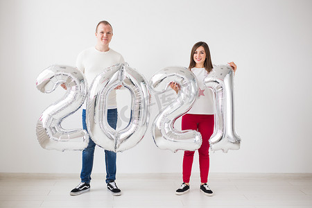 2021 年即将到来的概念 — 快乐的年轻男女在室内拿着银色数字。