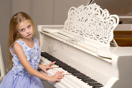 白色古典摄影照片_女孩站在白色三角钢琴前。