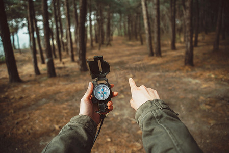 ppt罗盘摄影照片_有指南针的徒步旅行者在森林中指向方向