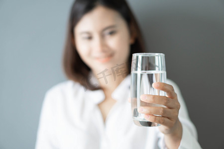 特写女人手拿着一杯纯净水，脸上带着笑脸