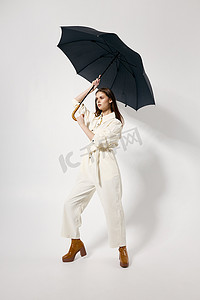 撑着雨伞摄影照片_身穿白色西装、头顶撑着雨伞、摆出完全成长姿势的女人