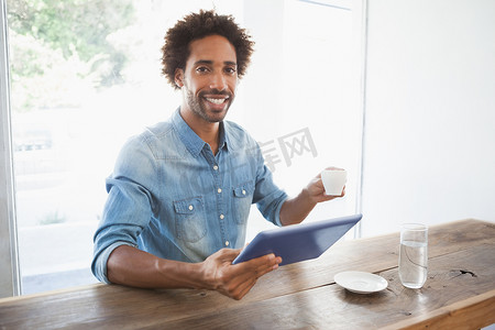 使用平板电脑时喝咖啡的休闲男士