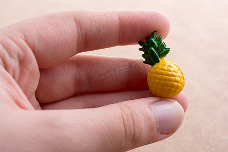 手拿着背景上的小菠萝模型