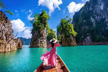美丽的女孩站在船上，望着泰国素叻他尼省考索国家公园 Ratchaprapha 大坝的群山。