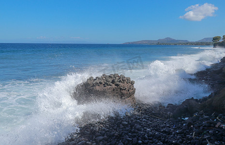 海浪拍打在石滩上，形成一个大浪花。