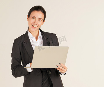 一位穿着黑色西装的女商人在电脑笔记本上打字。