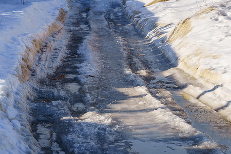 用冰雪覆盖的冬季道路，有水坑和车辙