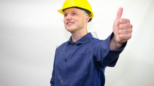 一位面带美丽笑容的年轻建设者，头戴头盔，在白色背景上，展示手指手势，一切都会好起来的。