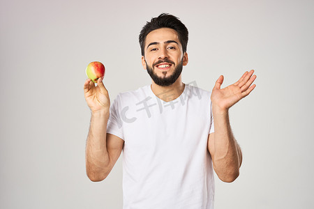 穿着白色T恤、手里拿着苹果的快乐男人，手里拿着健康水果