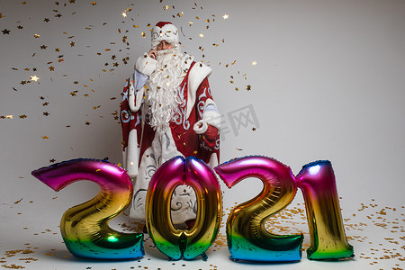 2021年新年庆祝活动，圣诞老人带着彩色气球和灰色工作室背景的五彩纸屑，复制空间