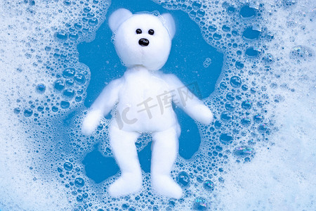 将小熊玩具浸泡在洗衣粉水中溶解后再清洗