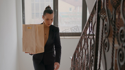 女商人在初创公司办公室爬楼梯，拿着外卖食品餐袋