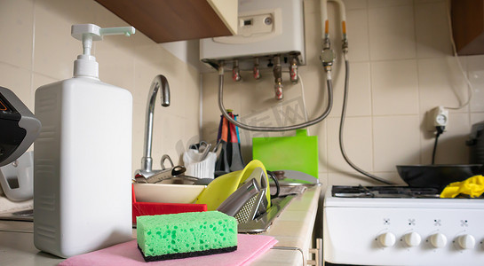 绿色海绵和液体肥皂分配器，用于在脏水槽上完全用餐具和厨房用具清洗餐具。