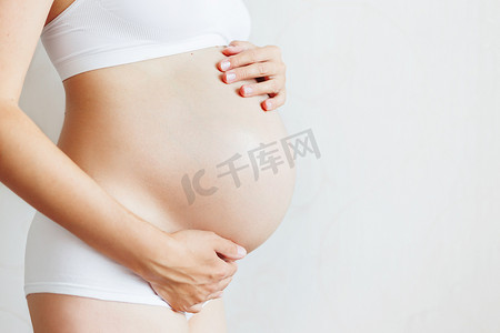 幸福孕妇摄影照片_白色内衣的孕妇。