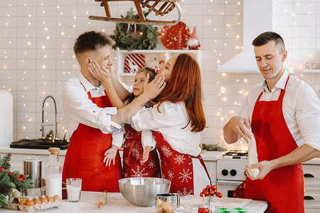 红色话剧摄影照片_一个幸福的家庭站在圣诞厨房里，互相抹面粉