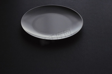 高级黑色背景摄影照片_黑色背景的空盘子、假日晚餐的高级餐具、简约的设计和饮食