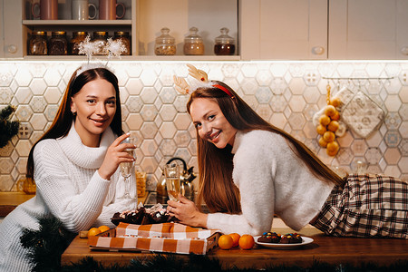 圣诞节时，两个女孩在舒适的家庭环境中，手里拿着香槟。