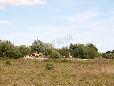 野外施工摄影照片_黄色停放在田野外远处的固定拖拉机