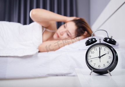 女人睡觉摄影照片_时钟与女人在床上失眠