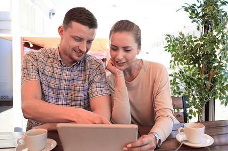 使用数字平板电脑在咖啡馆里调情的情侣。